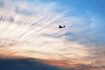 Small airplane silhouette in the sky at dramatic sunset. Romantic airborne evening