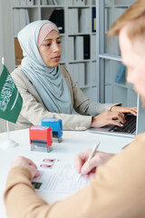 Selective focus shot of Muslim woman wearing hijab working as consular officer in embassy having...