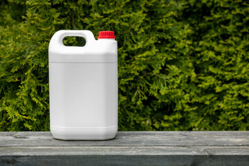 white blank plastic fertilizer jerry can for conifer garden plants. copy space