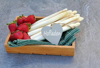 Weißer Spargel und Erdbeeren mit dem Text Hofladen auf einem Herz.