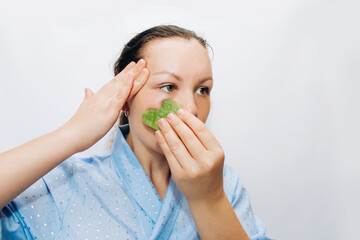 The girl makes a massage with a jade massager close-up, problem skin.