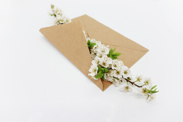 A branch of a blossoming apple tree and an envelope lie on a white table
