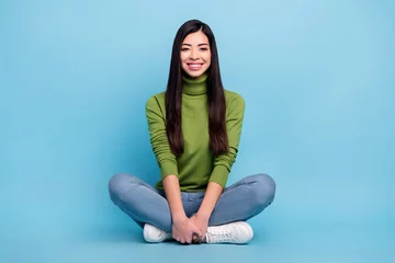 Poster Portrait of attractive cheerful glad confident girl sitting lotus pose shopping day isolated over bright blue color background © deagreez