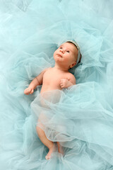 Infant baby princes with crown lye in cloud of pastel blue background and look up