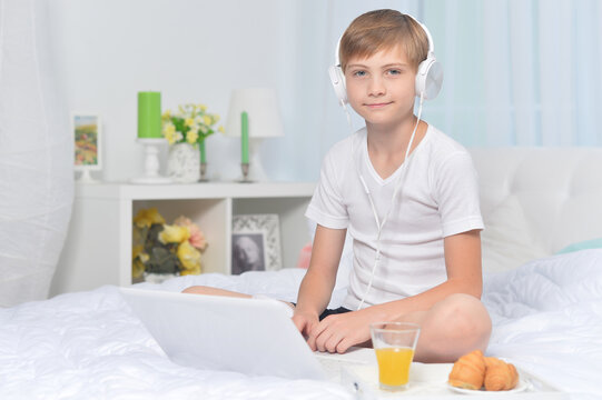 Boy listening to music on bed  while having breakfast