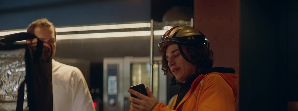 CU Portrait Of Courier Picking Up Order For Delivery From A Restaurant Kitchen. Shot With 2x Anamorphic Lens