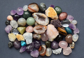 Tumbled and rough gemstones and crystals of various colors on  a grey background. Amethyst, geode...