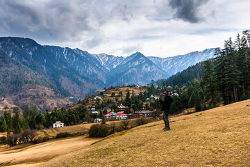 Young woman traveller looking towards the Himalayas mountains in Sainj Valley, Great Himalayan National Park, Himachal