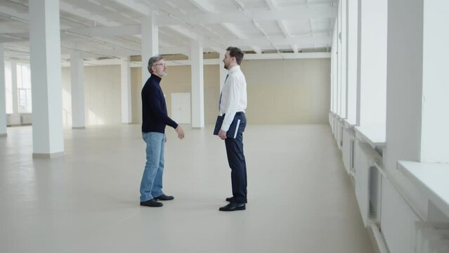 Businessman shakes hands with realtor at meeting to discuss an office lease agreement, side view. Realtor shakes hands with businessman, discussing lease agreement