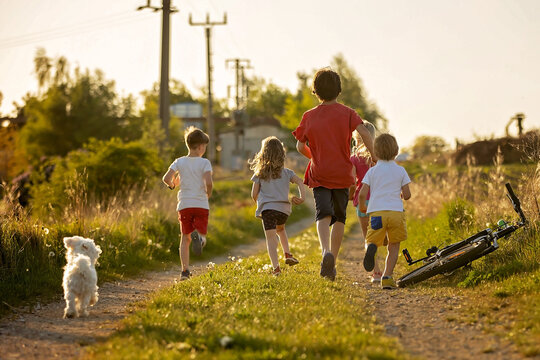Happy group of children and pet dog, maltese breed, running in the park on sunset, carefree childhood