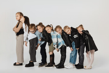 Obraz premium Group of happy cute kids, little girls and boys in modern outfits standing isolated on grey studio background. Beauty, kids fashion, education, happy childhood concept.