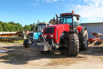 Agricultural machinery, tractors and equipment outdoors, near the garage, ready to work in the field.