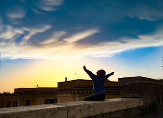 young girl is viewing city Rome and enjoying warm sunset