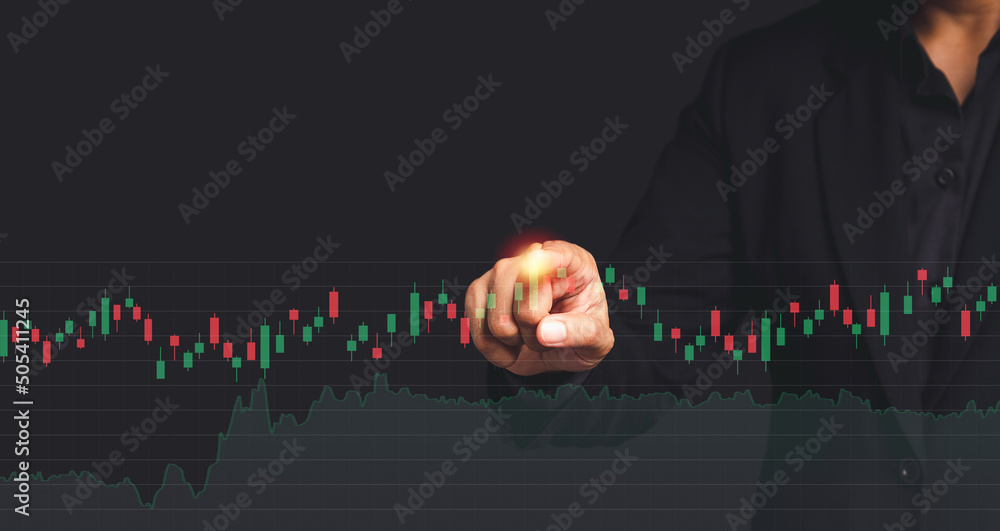 Poster hand of a businessman in a black suit pointing to graph stock on a virtual screen while standing on 