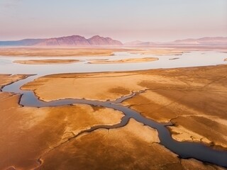 The shore of the Krasnoyarsk reservoir without water, sandbanks, clay and hills, riverbeds and channels, rainy sky over Mount Tepsey Tepsei