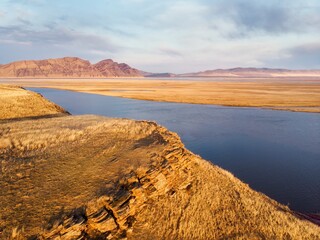 Rocks on the shore of the Krasnoyarsk reservoir without water, riverbed, sunset and rainy sky over Mount Tepsey Tepsei