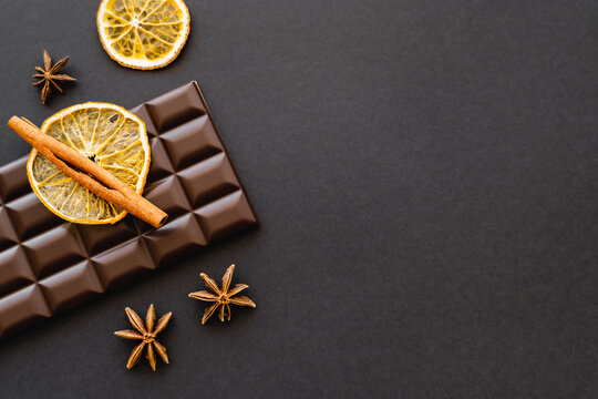 Top view of cinnamon, anise and orange slice on chocolate on black background.