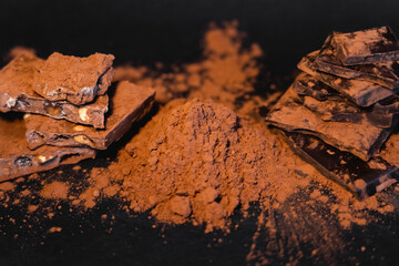 Close up view of natural cocoa powder and chocolate on black background.