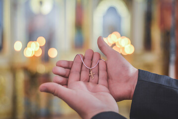 The priest holds a golden pectoral cross in his hands.
Golden cross close-up against the background...