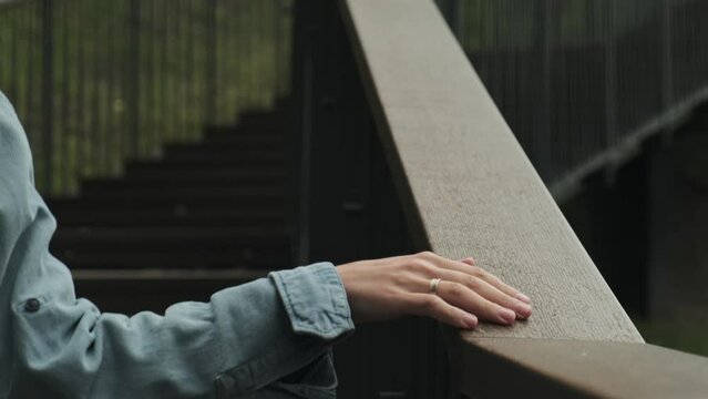 Woman's hand slides on a wooden handrail. Close-up view of a woman's hand touching a handrail while walking