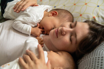 Happy mother lying in bed with baby daughters in the morning