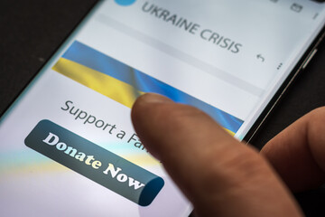 Close-up finger pressing donate icon button on smartphone screen. Donation money online concept