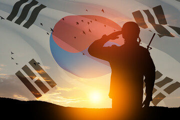 Silhouette of soldier saluting against the sunrise or sunset and South Korea flag. Concept - armed...