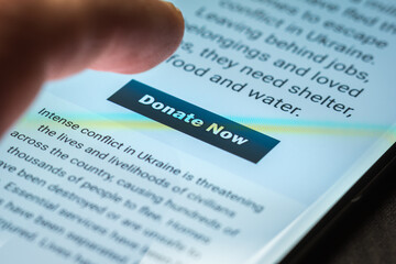 Close-up finger pressing donate icon button on smartphone screen. Donation money online concept