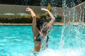 Woman swimming, splashing, and floating in pool. 