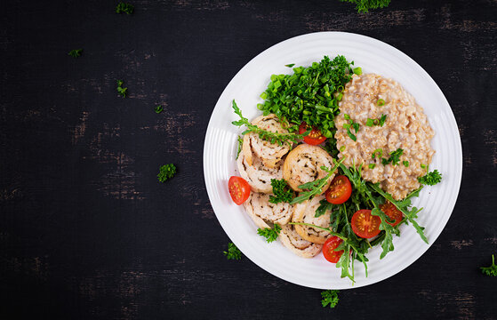 Brunch or lunch. Plate with oatmeal, chicken fillet, tomato and green herbs. Health food. Top view, overhead