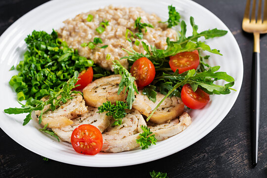 Brunch or lunch. Plate with oatmeal, chicken fillet, tomato and green herbs. Health food.