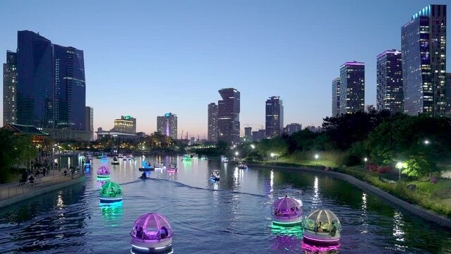 Songdo, Incheon. Night view of the lakeside with Skyscrappers. Pedal boat with led lamp on the lake.