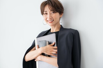 手帳とパソコンを持つ笑顔の日本人女性 - obrazy, fototapety, plakaty