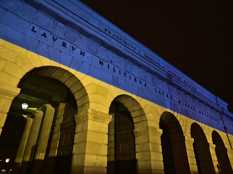 Vienna, Austria - 03-19-2022: Low angle view of historic gate &Auml;u&szlig;eres Burgtor in of Vienna, Austria by night with blue and yellow illuminations in the colors of the Ukrainian flag.