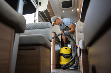 Cleaning Motorhome Camper Van Interior. Caucasian Worker in His 40s with Industrial Grade Vacuum Cleaner. Recreational Vehicles Theme. - obrazy, fototapety, plakaty