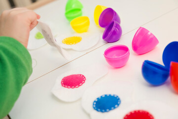 Happy Easter theme. Kid sorting eggs and learning colors. Montessori format task for kids education. Preschool toy for fine motor skils and training of imagination.