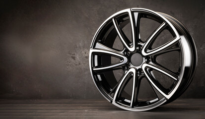 new stylish black alloy wheel on a textured background. aluminum wheel, auto parts