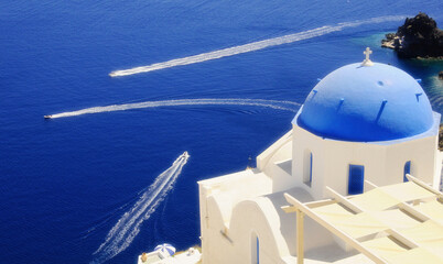 The white church in the town of Oia on the island of Santorini in Greece, and the trails over the sea of fast ships