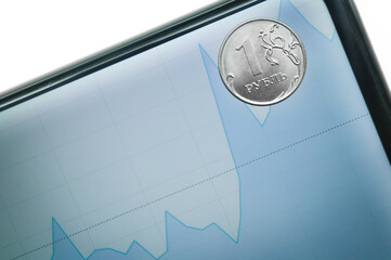 Coin is one ruble on screen of a smartphone with an exchange chart of value. Growth and fall of the...