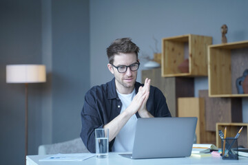 Young handsome austrian male freelancer wearing glasses looking at computer screen attentively