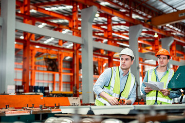 Fototapeta na wymiar Two male industrial engineers wearing helmets are checking the neatness of the industrial machines. for safe use
