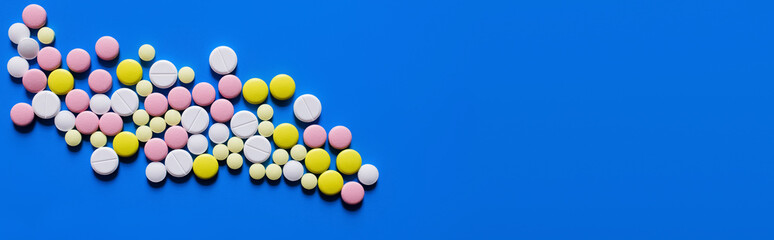 flat lay view of different round shape pills on blue background, banner.