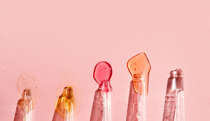 Pipettes with fluid hyaluronic acid on pink background in the sunlight. Cosmetics and healthcare...