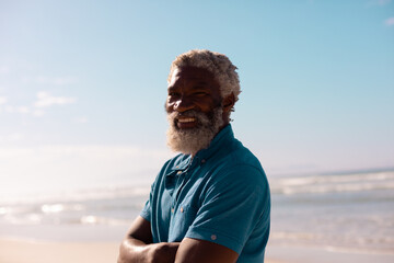 Portrait of smiling bearded african american senior man with gray hair standing against sea and sky
