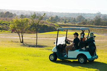 Multiracial young male friends riding in golf cart against clear sky at golf course in summer