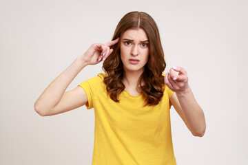 You are stupid! Self confident egoistic teenager girl wearing yellow T-shirt holding finger near...
