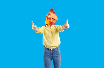 Creative advertising. Cheerful funny and humorous woman in rubber mask of chicken shows thumbs up...