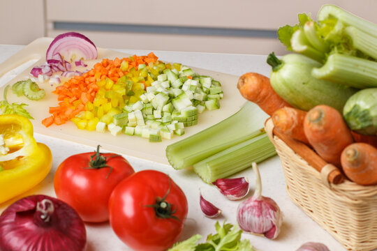 Chopped fresh vegetables for cooking. Carrots, zucchini, celery, bell pepper, tomatoes, garlic and red onion on a cutting board. Culinary ingredients. Healthy eating. Diet. Selective focus