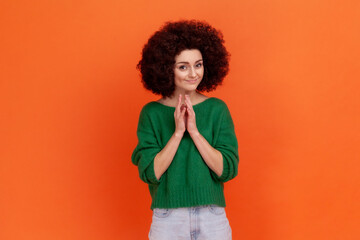 Cunning young adult woman with Afro hairstyle wearing green casual style sweater having tricky...