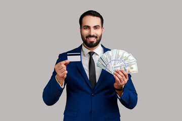 Portrait of smiling bearded businessman holding credit card and lot of money, being glad by cash...